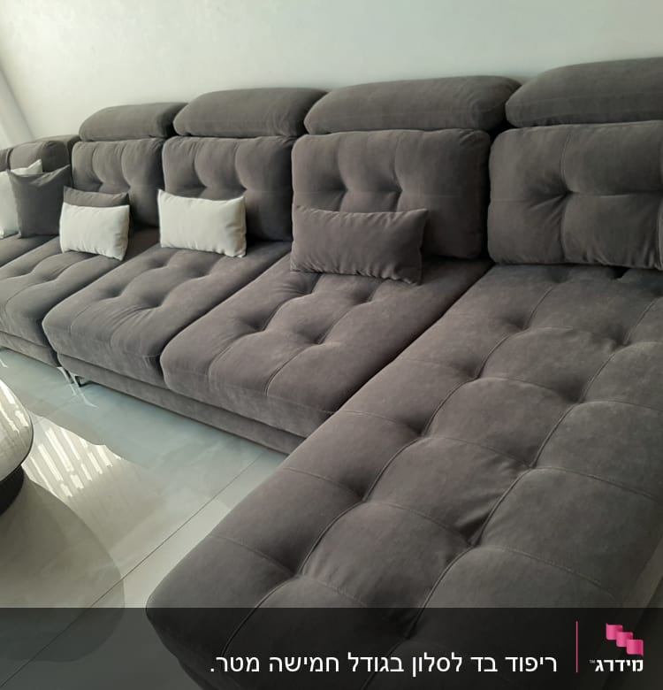 ספה אפורה עם כריות לבנות על ריצוף מבריק